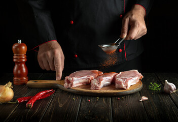 Professional chef sprinkles paprika on fresh ribs close-up. Dark background for recipe book or...