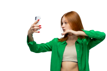 Cool ginger teenager girl making selfie on smartphone. Cute young woman isolated over white background. Adolescence addiction to digital gadget and social media. Copy space.