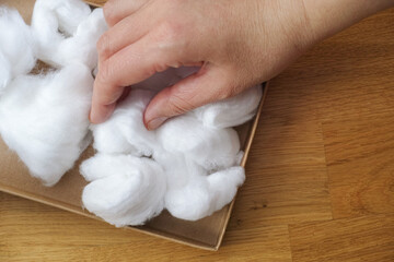 A woman taking a cotton ball out of a cardboard box