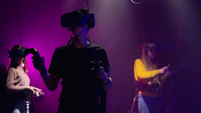 Group of people playing VR games in a studio with blue pink neon lights