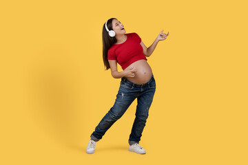 Fototapeta na wymiar Positive Pregnant Woman Listening Music In Wireless Headphones And Playing Air Guitar