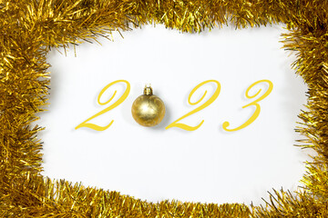 The coming of 2023. Christmas toys and tinsel of gold color on a white background. new year concept
