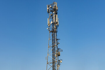 5G antenna communication tower with dish against a clear blue sky