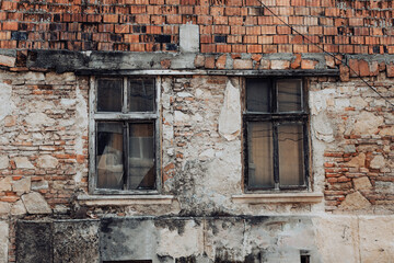 Damaged abandoned construction made of bricks and concrete with windows that have broken or shattered glass