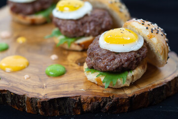 mini hamburguesas de copetin con huevo en tabla de madera