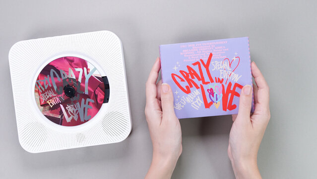 Fan hands holding 1st music album of k-pop group Itzy CRAZY IN LOVE on grey background. Pink music CD in white retro player. South Korean girl group Itzy. Gatineau, QC Canada - November 10 2022