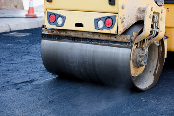 Road roller and asphalt paving machine at construction site