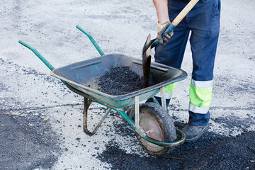 asphalt in wheelbarrow operator prepares mixture with uniform