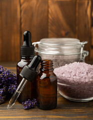 Lavender flowers, fragrant sea salt and essential oils. The concept of spa, beauty and health salon, skin care cosmetics. Natural cosmetics.Aroma procedures. Closeup on brown texture background.