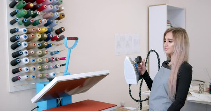 Young woman taylor ironing fabric on a table
