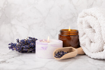 Obraz na płótnie Canvas Lavender flowers and scented candle. The concept of spa, beauty and health salon, skin care cosmetics. Natural cosmetics.Aroma procedures. Closeup on white marble background.