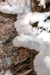 Winter landscape with snow-covered rocks and grass on the river bank