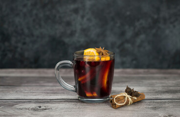 Mulled wine with orange in a glass on grey and brown background.