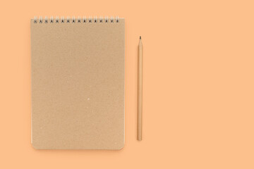 Beige working notebook and pencil for notes on a beige background. Place for text.