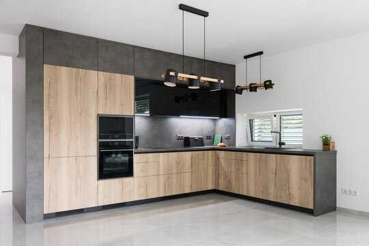 Combination of black and wood in modern kitchen with built in appliances
