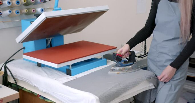 Young woman taylor ironing fabric on a table