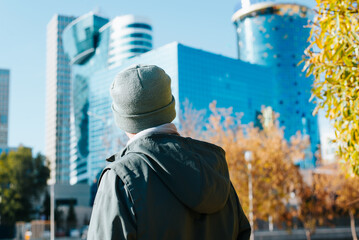 Tourist viewing modern urban environment, high-rise buildings, outdoors. Back view of an...