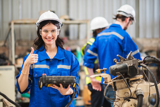 Industrial female engineers maintenance robot arm in factory. Automation technician engineer using controller for control welding machine in manufacturing Industry.