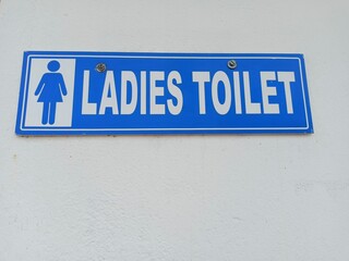 toilet sign board with blue background on the wall. only ladies ladies are allow.