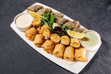 Baked pies with fish and sauce on a white plate. Decorated with herbs and lemon. Restaurant dish, restaurant and food concept.