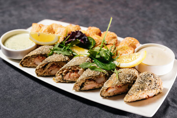 Baked pies with fish and sauce on a white plate. Decorated with herbs and lemon. Restaurant dish, restaurant and food concept.