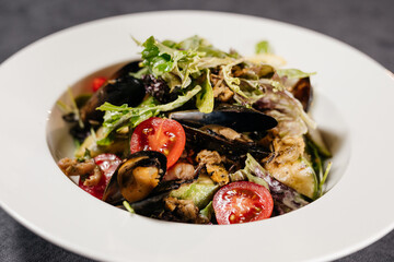 Salad with mussels on a white plate, decorated with greens. Restaurant concept.