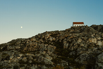 small house on the top of the rock, sky with moon, mountains