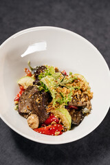 Salad with veal on a white plate, decorated with onion crisps. Restaurant concept.