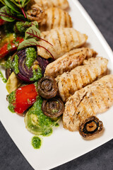 Grilled chicken breast with grilled vegetables, garnished with pesto sauce. Restaurant concept.