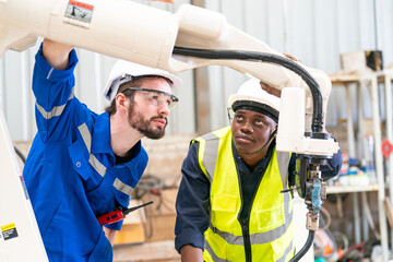 Robotics engineer working on maintenance of modern robotic arm in factory warehouse