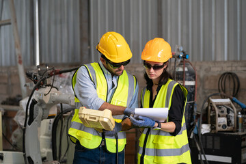 Robotics engineer working on maintenance of modern robotic arm in factory warehouse