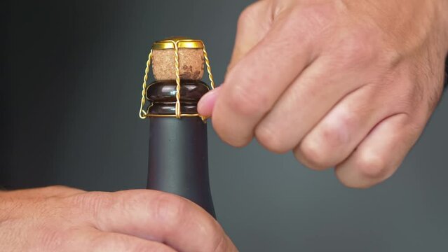 New year celebration, opening champagne bottle. Male hands and wooden cork