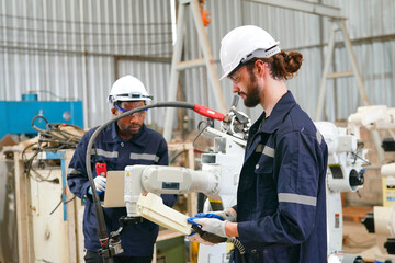 Robotics engineer working on maintenance of modern robotic arm in factory warehouse