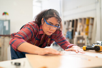 A furniture workshop making bespoke contemporary furniture pieces using traditional skills in modern design. A man in ear defenders holding wood, using a machine.
