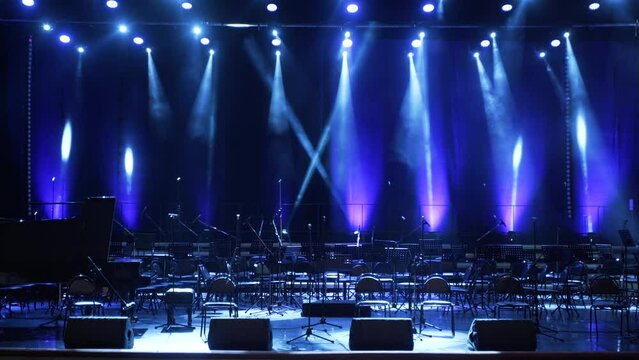 Concert light. Stage lighting background. An empty stage and a hall without people. There are a lot of empty chairs and microphones on the stage for musicians.