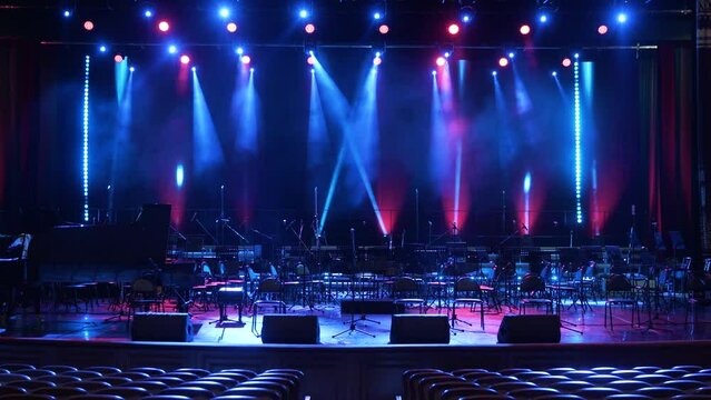 Concert light. Stage lighting background. An empty stage and a hall without people. There are a lot of empty chairs and microphones on the stage for musicians.