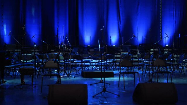 Concert light. Stage lighting background. An empty stage and a hall without people. There are a lot of empty chairs and microphones on the stage for musicians.
