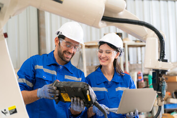 Robotics engineer working on maintenance of modern robotic arm in factory warehouse