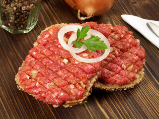 Spicy Beef Tartar Meat on a Bread Roll with Onions on wooden Background