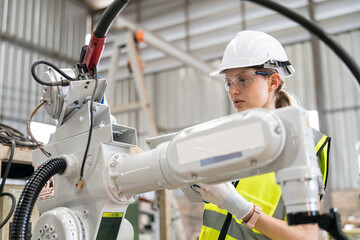 Robotics engineer working on maintenance of modern robotic arm in factory warehouse