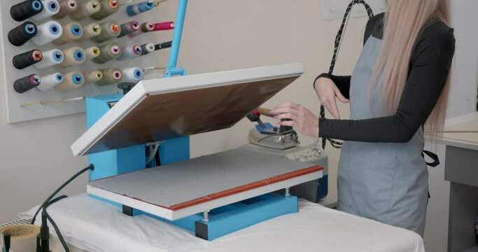 Young woman taylor ironing fabric on a table