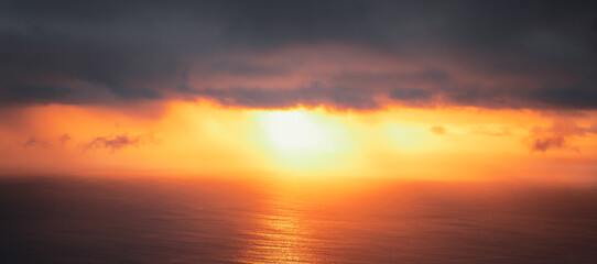 Amazing scenic view from a madeira trip at amazing sunsetlight in the mountsina with a view down to the sea in a moody and foggy but also bright weather.