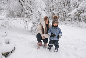 Fototapeta na wymiar Mom and son are walking in the snow in the forest.