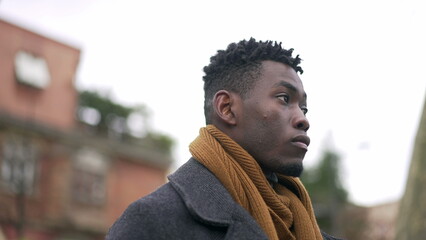 Serious black African man standing at park wearing winter clothing thinking about life2