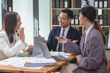 A team of businessmen plan with their laptops and graph charts for their profits and use a calculator to calculate their company is annual balance.