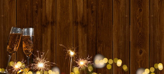 New Year Sylvester festive celebration holiday New Year's Eve greeting card banner - Toasting Champagne or sparkling wine glasses and sparkling sparklers, background brown wooden wall texture - obrazy, fototapety, plakaty