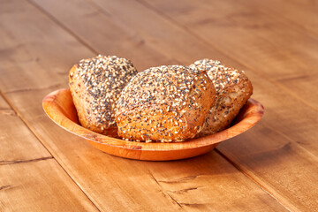 Bun with poppy seeds and sesame on the wooden table.