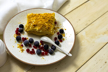 Napoleon cake with berries on a wooden table