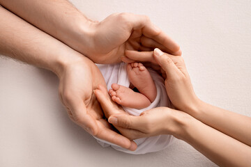 Legs, toes, feet and heels of a newborn. With the hands of parents, father, mother gently holds the child's legs. Macro photography, close-up. Black and white photo. High quality photo