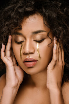 curly african american woman with golden tears on cheeks and closed eyes.
